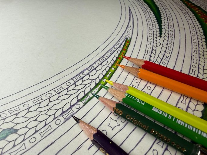 Bunte Bleistifte liegen neben einem Ausmalbild mit geschwungenen Linien.