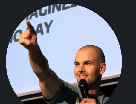 Ein Mann spricht vor einem Bildschirm und zeigt nach vorne.